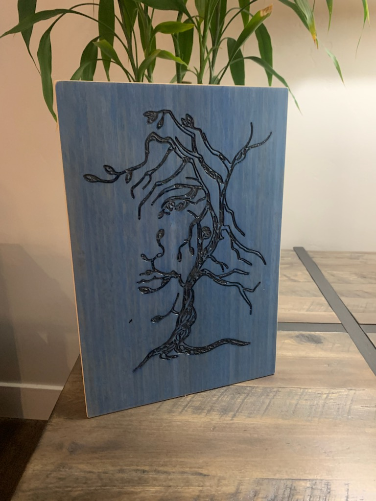 Blue-stained wood panel with laser-carved tree design