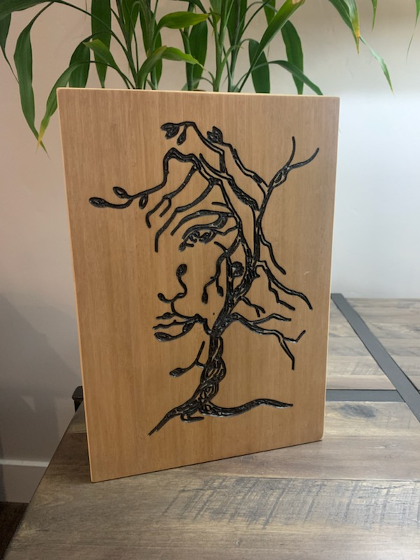 Light brown wood panel with laser-carved tree design